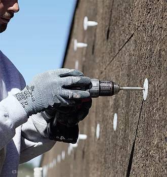 ouvrier Iso-Renov entrain de fixer des plaques isolantes Webertherm XM Natura sur une façade