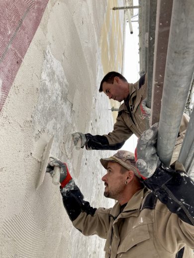 ouvriers Iso-Renov entrain d'étaler de l'enduit sur une trame en fibre de verre posée sur une façade