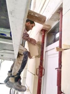 ouvrier Iso-Renov entrain de réparer des pierres de taille sur une façade